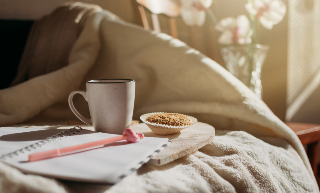 notepad, pen, coffee, and muffin on a bed; morning routine for busy moms
